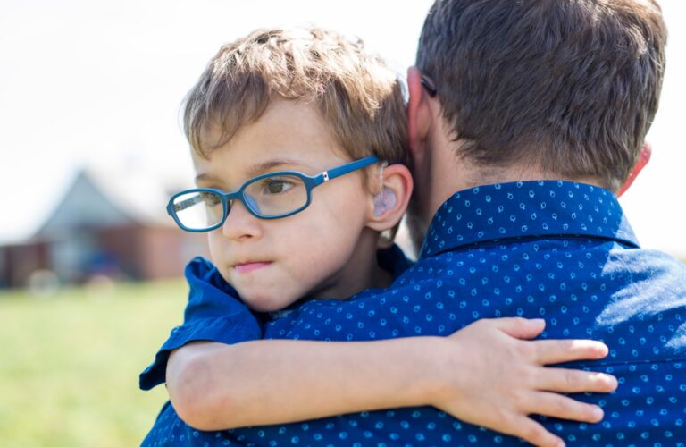 Jeune enfant en situation de handicap dans les bras de son papa